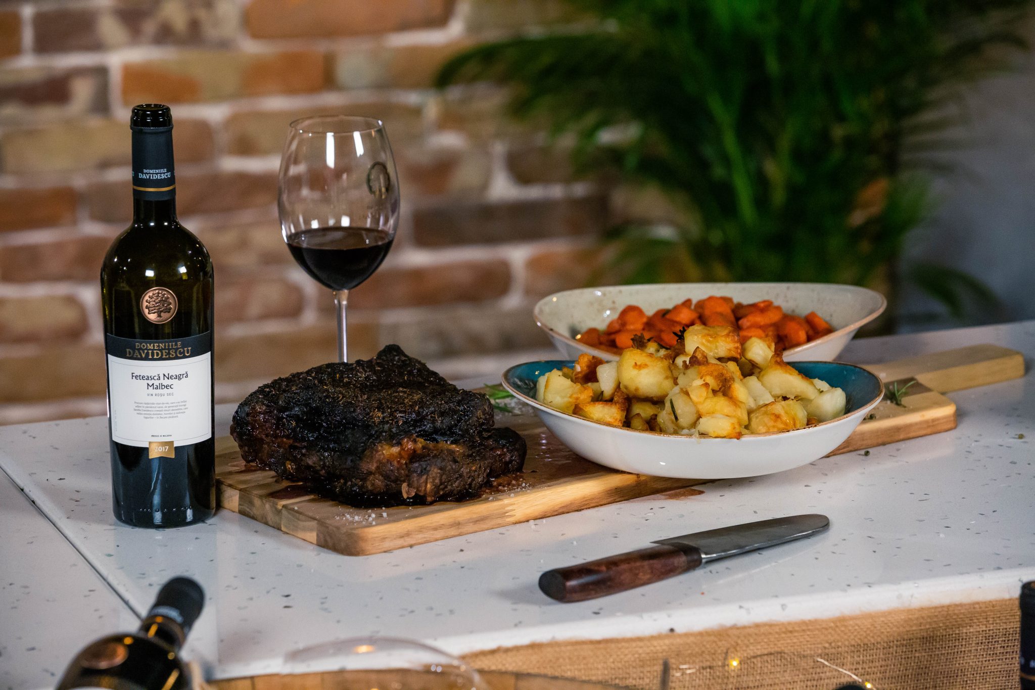 sticla vin rosu Malbec, alaturi de branzeturi si mezeluri pe un tocator